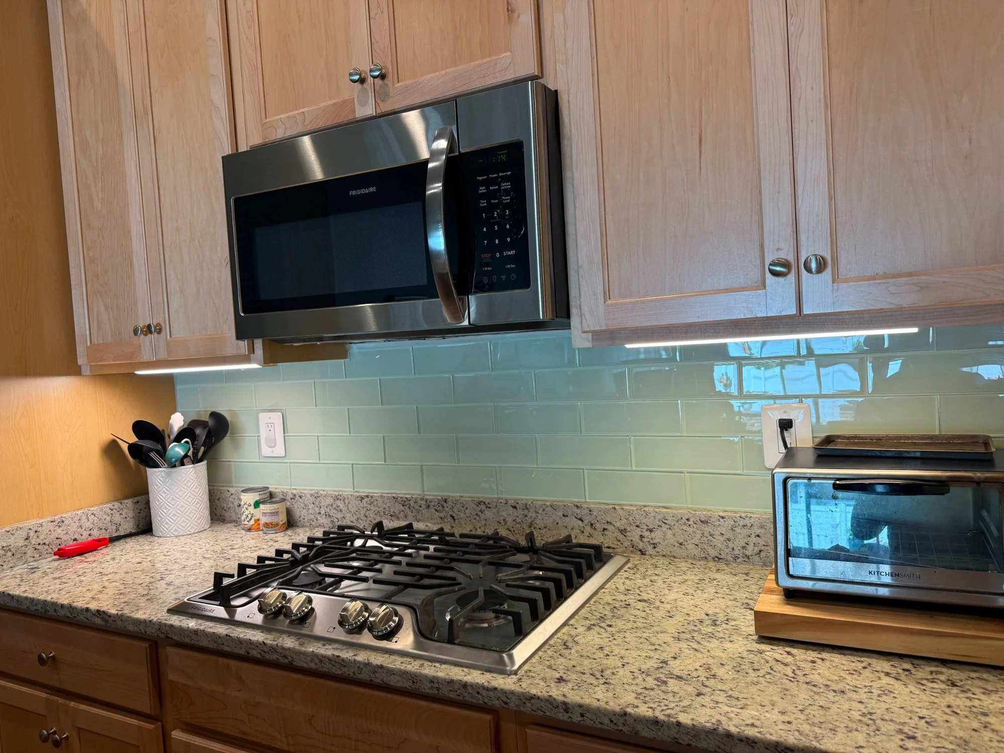Professionally cleaned residential kitchen with polished cooktop, counters, backsplash, and microwave